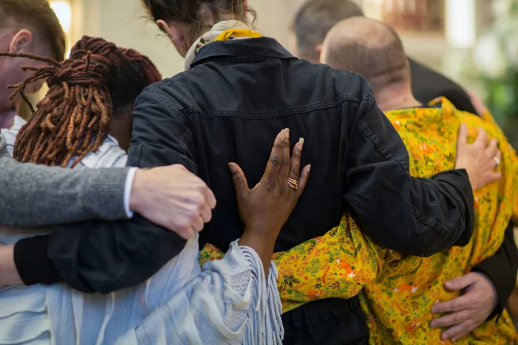 Famille et proches enlacés en signe de solidarité et de recueillement pendant un hommage.
